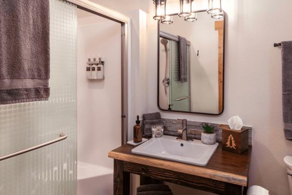 Bright cabin bathroom with a wood vanity, large mirror, modern sink, and clean, simple finishes.