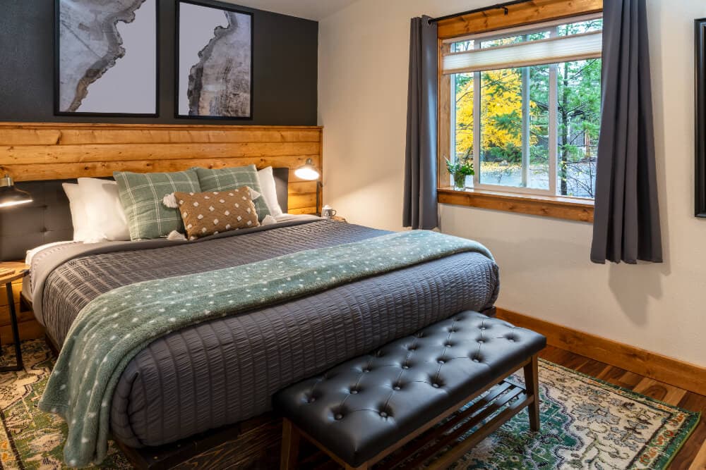 Cozy bedroom with a king-size bed, decorative pillows, and large window overlooking a vibrant outdoor scene.