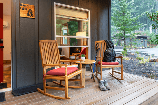 Cozy cabin porch with wooden chairs, and peaceful views of golden autumn trees.