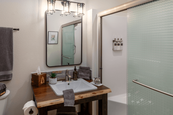 Bright cabin bathroom with a wood vanity, large mirror, modern sink, and clean, simple finishes.