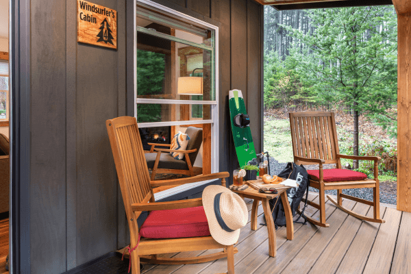 Cozy cabin porch with wooden chairs and peaceful views of trees.