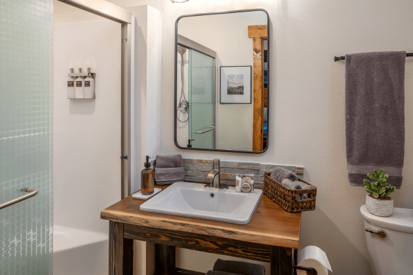Bright bathroom with a wood vanity, modern sink, large mirror, and clean, simple design.