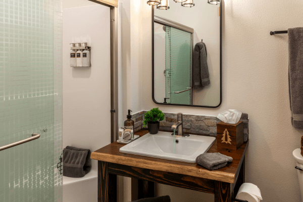 Bright cabin bathroom with a wood vanity, large mirror, modern sink, and clean, simple finishes.