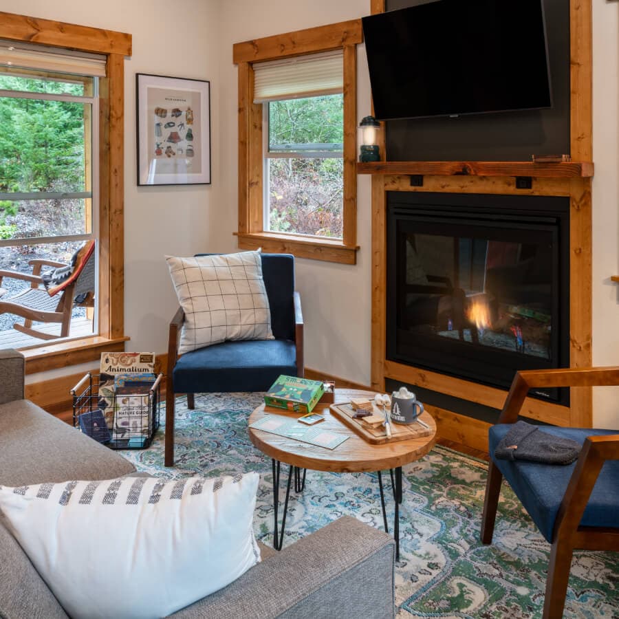 Cozy living room with a fireplace, two armchairs, a gray couch, and a wooden coffee table.