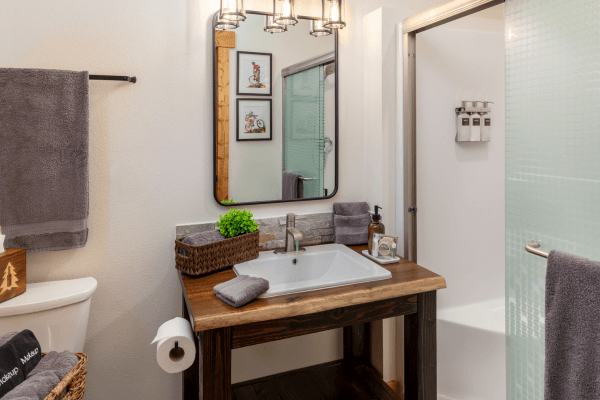 Bright cabin bathroom with a wood vanity, large mirror, modern sink, and clean, simple finishes.