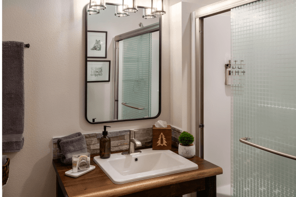 Bright cabin bathroom with a wood vanity, large mirror, modern sink, and clean, simple finishes.