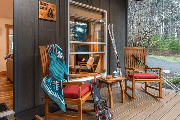 Cozy cabin porch with wooden chairs and peaceful views of trees.