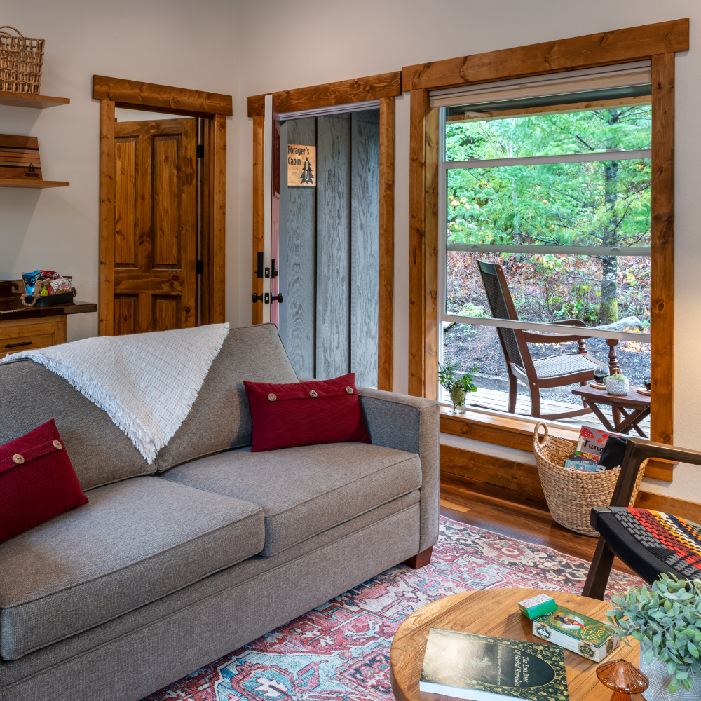 IMAGE OF SOFA AND VIEW OUT WINDOW TO ROCKING CHAIRS OF FORAGER'S CABIN AT BACKWOODS CABINS