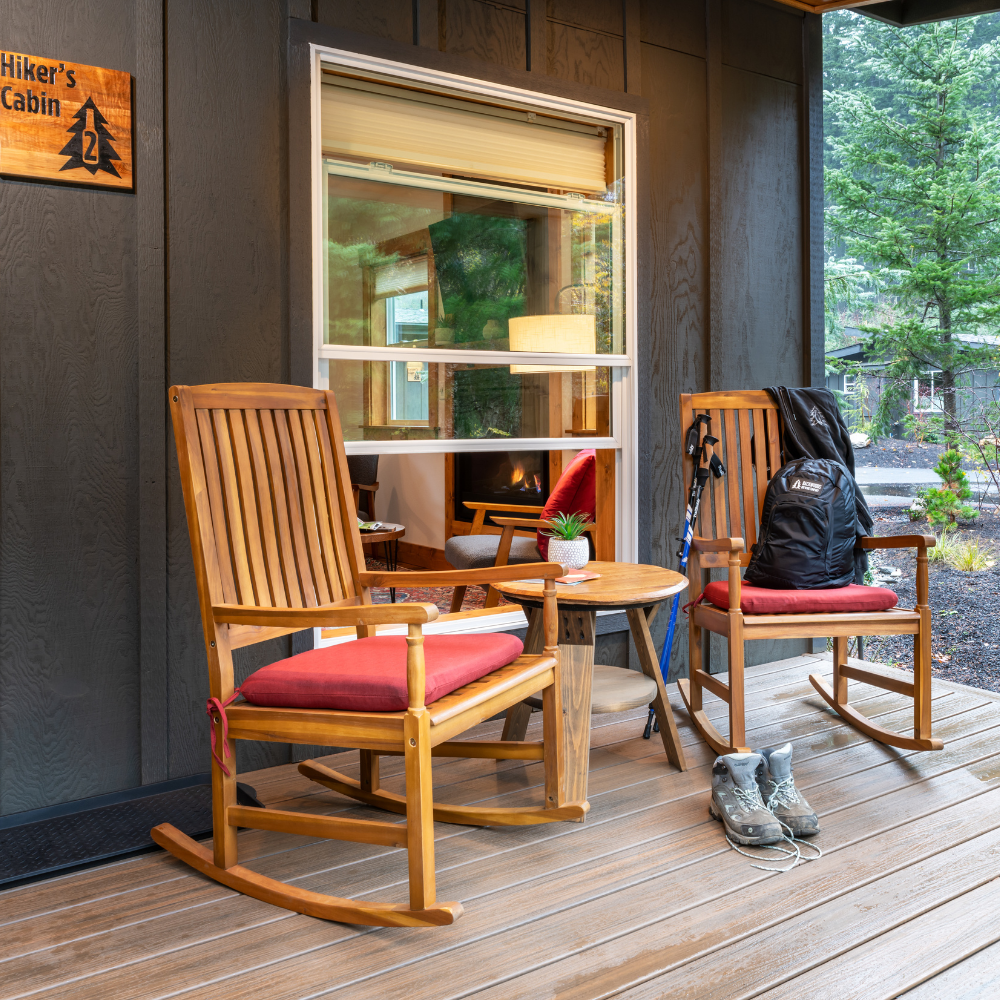 Image of Hiker's Cabin front porch with two rocking chairs, hiking boots, poles, and a backpack.
