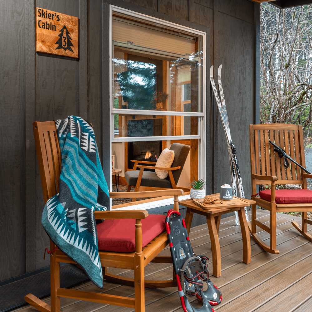 Image of rocking chairs with skies and snow shoes, blue blanket on cozy cabin porch in the Cascade Forest in Carson Washington at Backwoods Cabins.